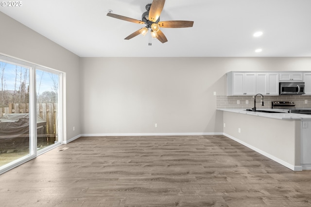 kitchen with backsplash, baseboards, light countertops, wood finished floors, and stainless steel appliances