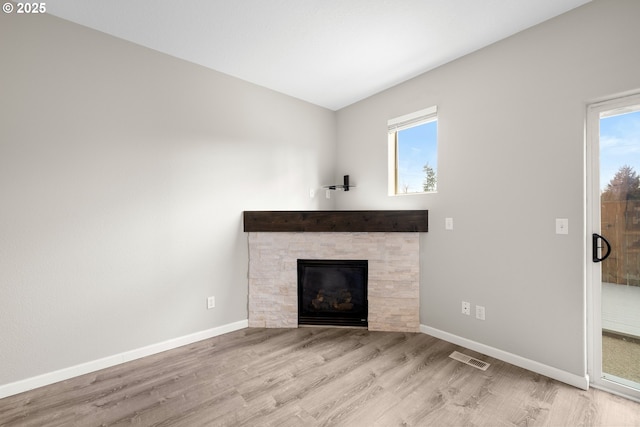 unfurnished living room featuring a wealth of natural light, baseboards, and wood finished floors