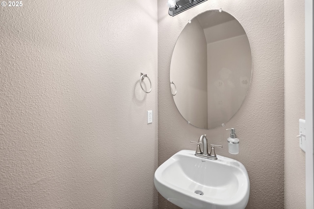 bathroom featuring a textured wall and a sink