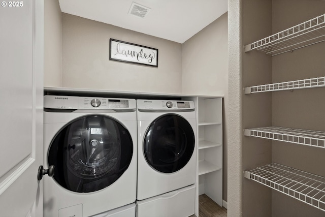 laundry room with laundry area, wood finished floors, visible vents, and separate washer and dryer