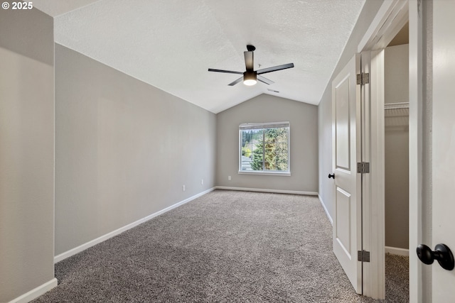 unfurnished bedroom featuring lofted ceiling, a ceiling fan, a textured ceiling, carpet floors, and baseboards