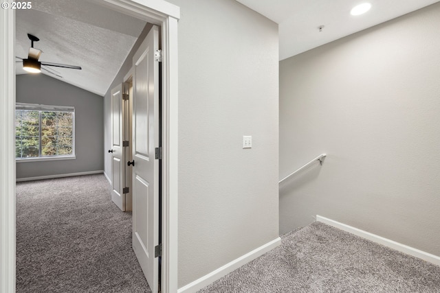 hall featuring an upstairs landing, baseboards, lofted ceiling, and carpet