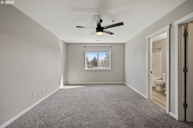 unfurnished bedroom featuring a ceiling fan, ensuite bathroom, a textured ceiling, carpet, and baseboards