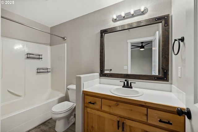 bathroom with vanity,  shower combination, toilet, and a textured wall