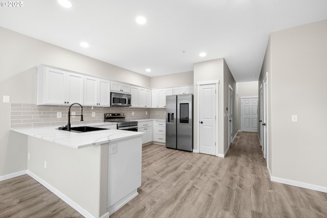 kitchen featuring backsplash, appliances with stainless steel finishes, a peninsula, and a sink