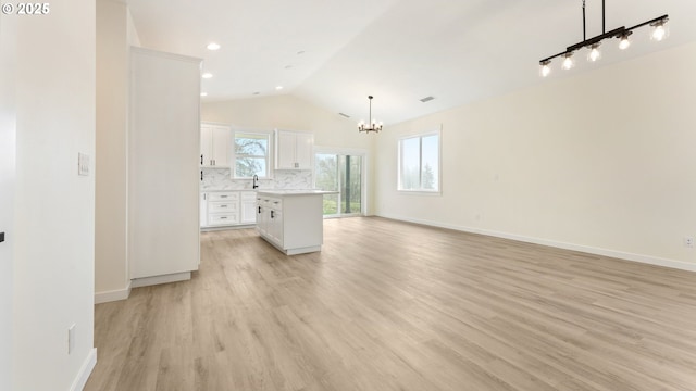 kitchen with light hardwood / wood-style flooring, white cabinetry, hanging light fixtures, a center island, and decorative backsplash