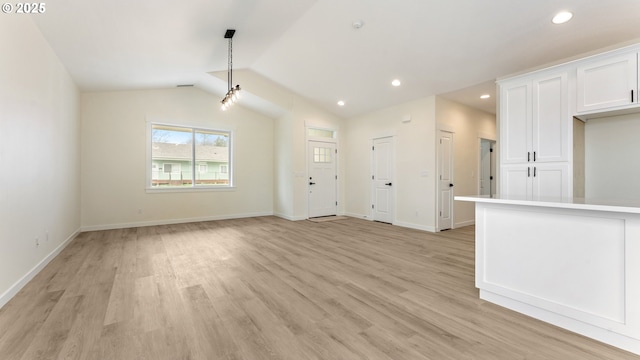 unfurnished living room featuring vaulted ceiling and light wood-type flooring