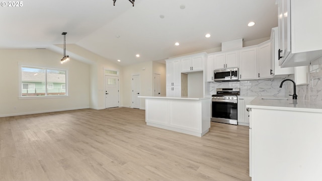 kitchen with sink, a kitchen island, stainless steel appliances, decorative backsplash, and white cabinets