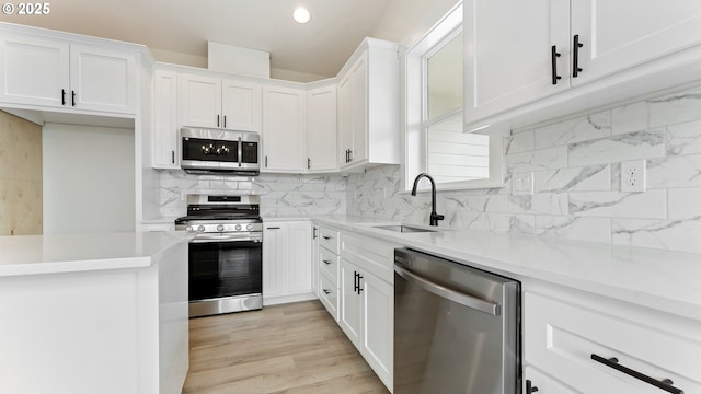 kitchen with sink, light hardwood / wood-style flooring, white cabinetry, stainless steel appliances, and decorative backsplash