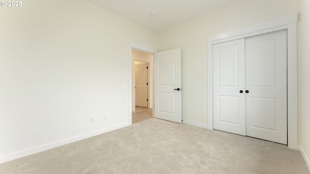 unfurnished bedroom with light colored carpet and a closet