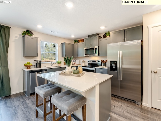 kitchen featuring a kitchen bar, stainless steel appliances, a center island, light hardwood / wood-style flooring, and sink