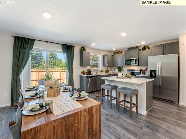 kitchen with hardwood / wood-style floors, a center island, sink, gray cabinetry, and stainless steel appliances