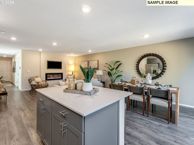 kitchen featuring a textured ceiling, gray cabinetry, light hardwood / wood-style flooring, and a center island