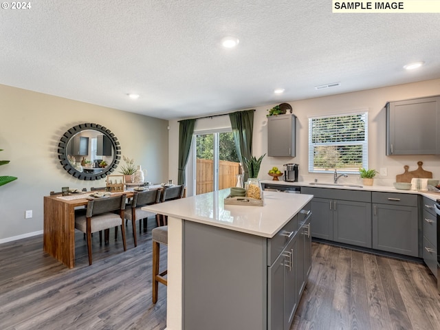 kitchen with dark hardwood / wood-style floors, gray cabinets, a kitchen island, sink, and a textured ceiling