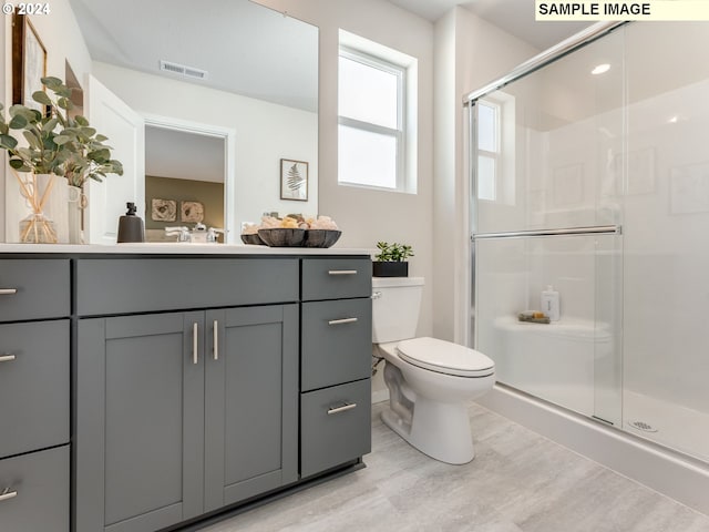 bathroom with toilet, vanity, and a shower with shower door