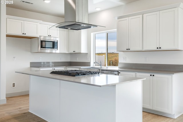 534 Grant St, Umatilla, OR 97882 - kitchen featuring island range hood, stainless steel appliances, a kitchen island, white cabinets, and light wood-style floors