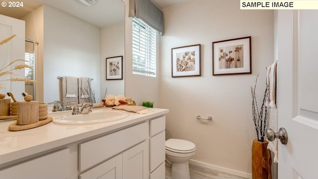 full bathroom with toilet, vanity, baseboards, and an enclosed shower