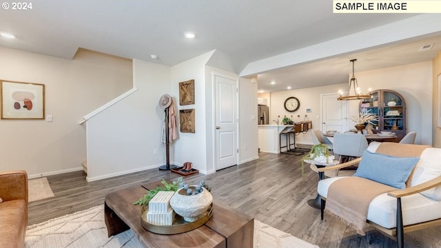 living room with baseboards, a notable chandelier, wood finished floors, and recessed lighting