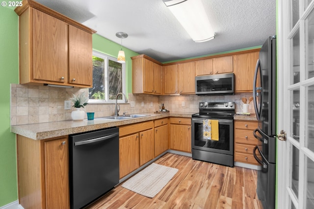1601 NW 2nd Ave, Battle Ground, WA 98604 - kitchen with stainless steel appliances, a sink, light wood-style floors, backsplash, and a textured ceiling