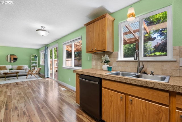 1601 NW 2nd Ave, Battle Ground, WA 98604 - kitchen featuring dishwashing machine, a sink, light wood-style floors, tile countertops, and decorative backsplash