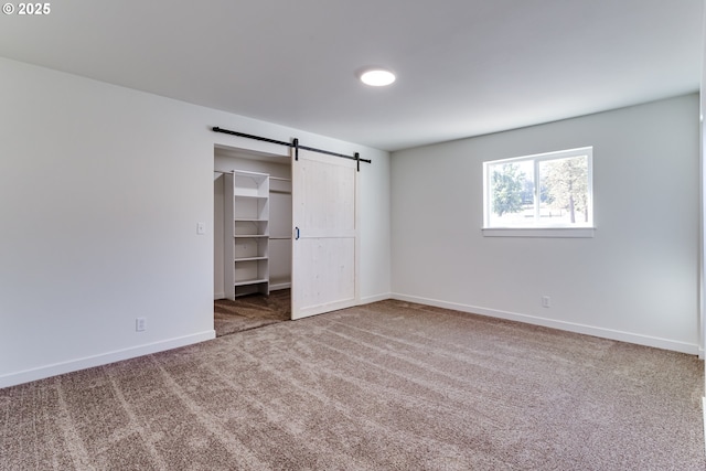 85160 Larson Rd, Eugene, OR 97405 - unfurnished bedroom featuring carpet flooring, a barn door, baseboards, a spacious closet, and a closet