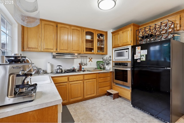 kitchen with black refrigerator, white microwave, oven, and light tile patterned flooring