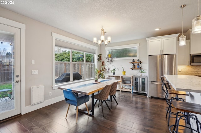 dining space with a chandelier, a textured ceiling, baseboards, and dark wood-style flooring