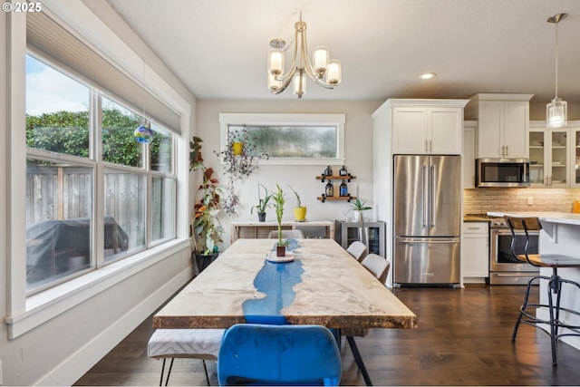 dining area featuring dark wood finished floors, an inviting chandelier, baseboards, and a wealth of natural light