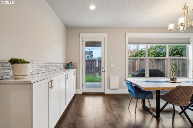 dining area featuring baseboards, a textured ceiling, a chandelier, and dark wood-style flooring