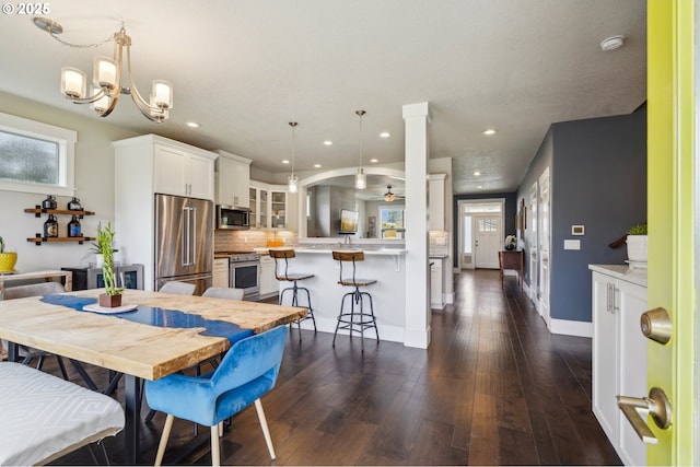 dining area featuring dark wood-style floors, recessed lighting, ceiling fan with notable chandelier, and baseboards