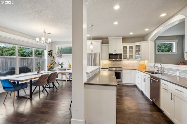 kitchen featuring a sink, premium appliances, tasteful backsplash, and dark wood finished floors