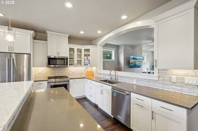 kitchen featuring a sink, premium appliances, tasteful backsplash, dark wood-style floors, and white cabinetry