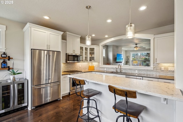 kitchen featuring a sink, a kitchen breakfast bar, wine cooler, and high end appliances