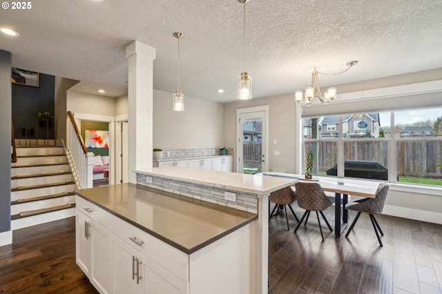 kitchen featuring a kitchen island, recessed lighting, dark wood-style flooring, hanging light fixtures, and white cabinetry