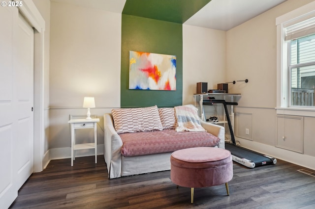 sitting room featuring a decorative wall, wood finished floors, and visible vents