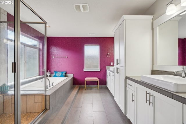 full bath with tile patterned flooring, a healthy amount of sunlight, two vanities, and a sink