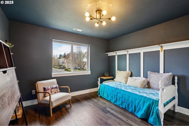 bedroom with baseboards, wood finished floors, visible vents, and a chandelier