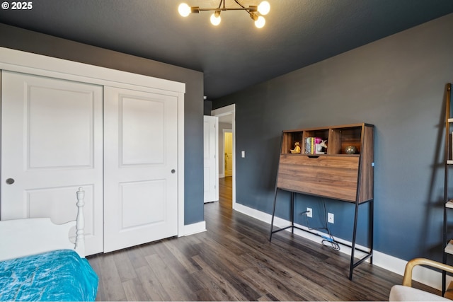 bedroom with dark wood finished floors, a chandelier, a closet, and baseboards