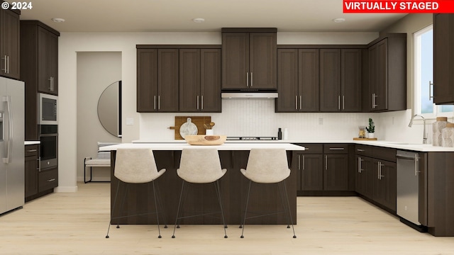 kitchen with dark brown cabinetry, a center island, stainless steel appliances, and light wood-style floors