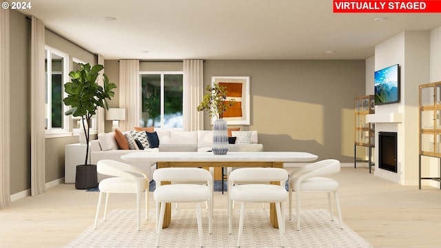 dining room with baseboards, light wood-style flooring, and a fireplace