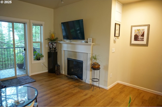living room featuring wood finished floors, a tile fireplace, and baseboards