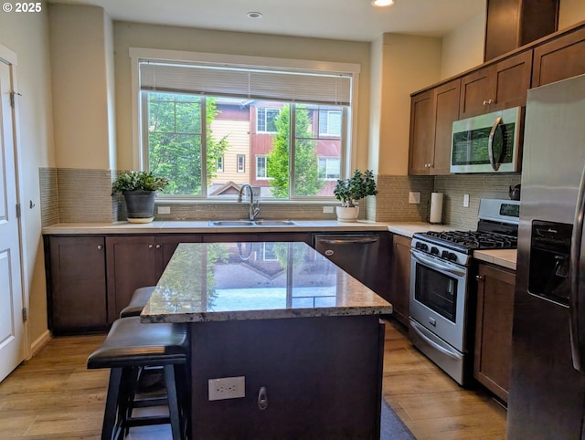 kitchen with appliances with stainless steel finishes, a sink, a kitchen island, healthy amount of natural light, and recessed lighting