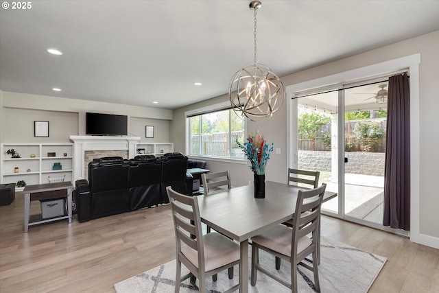 dining area featuring a fireplace, recessed lighting, an inviting chandelier, and light wood-type flooring