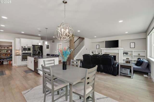 dining room with visible vents, a fireplace, a chandelier, recessed lighting, and light wood-style flooring