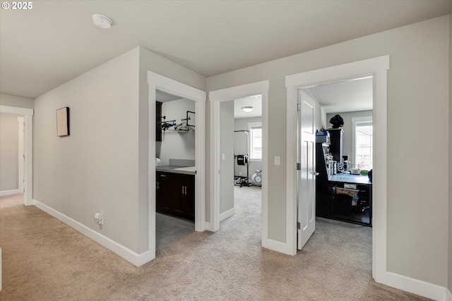 hall with baseboards and light carpet