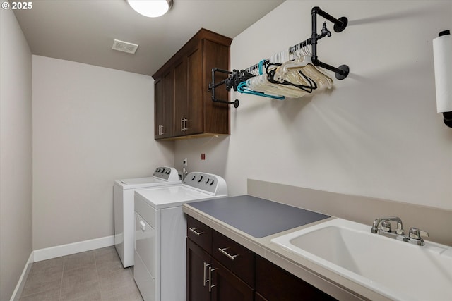 washroom with visible vents, washing machine and dryer, cabinet space, a sink, and baseboards