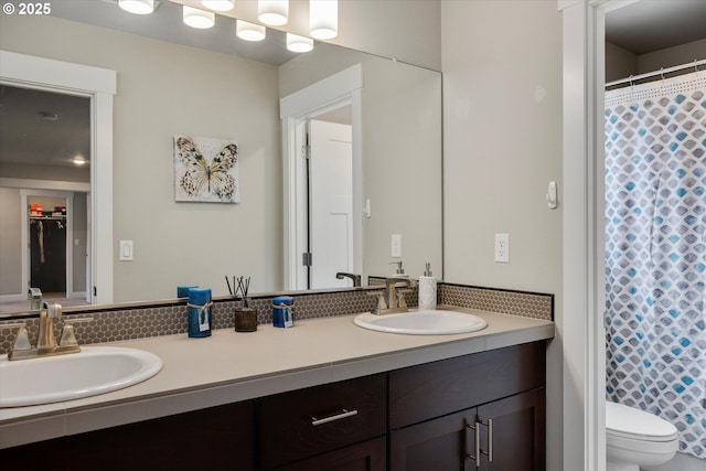 bathroom with a sink, curtained shower, toilet, and double vanity
