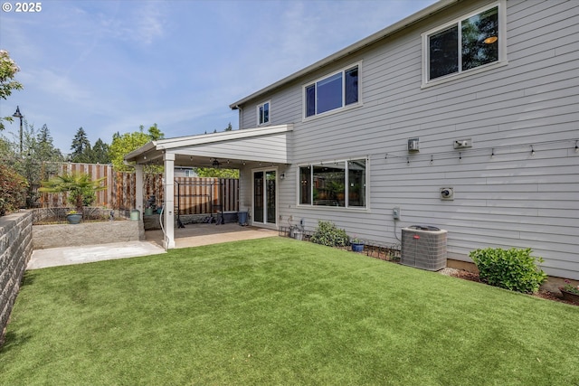 rear view of house featuring a lawn, a fenced backyard, a patio area, and central AC
