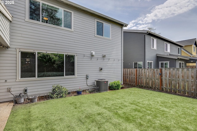 back of house featuring central AC, fence, and a yard