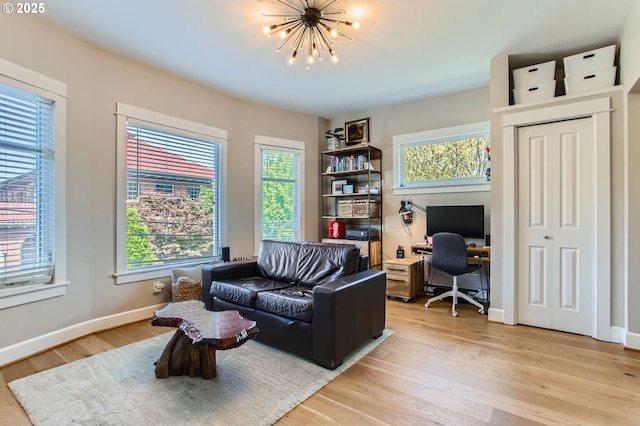 sitting room with baseboards, light wood finished floors, and a chandelier